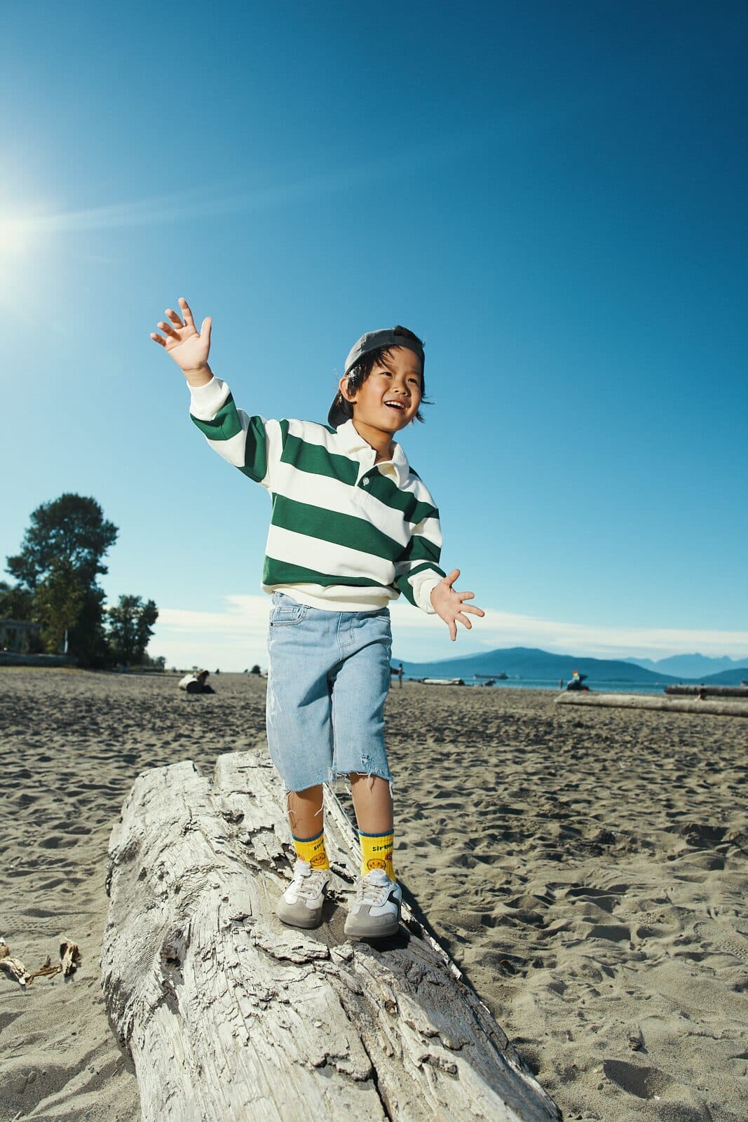 Lifestyle kids apparel campaign with child balancing on driftwood at a Vancouver beach by Una Zhu