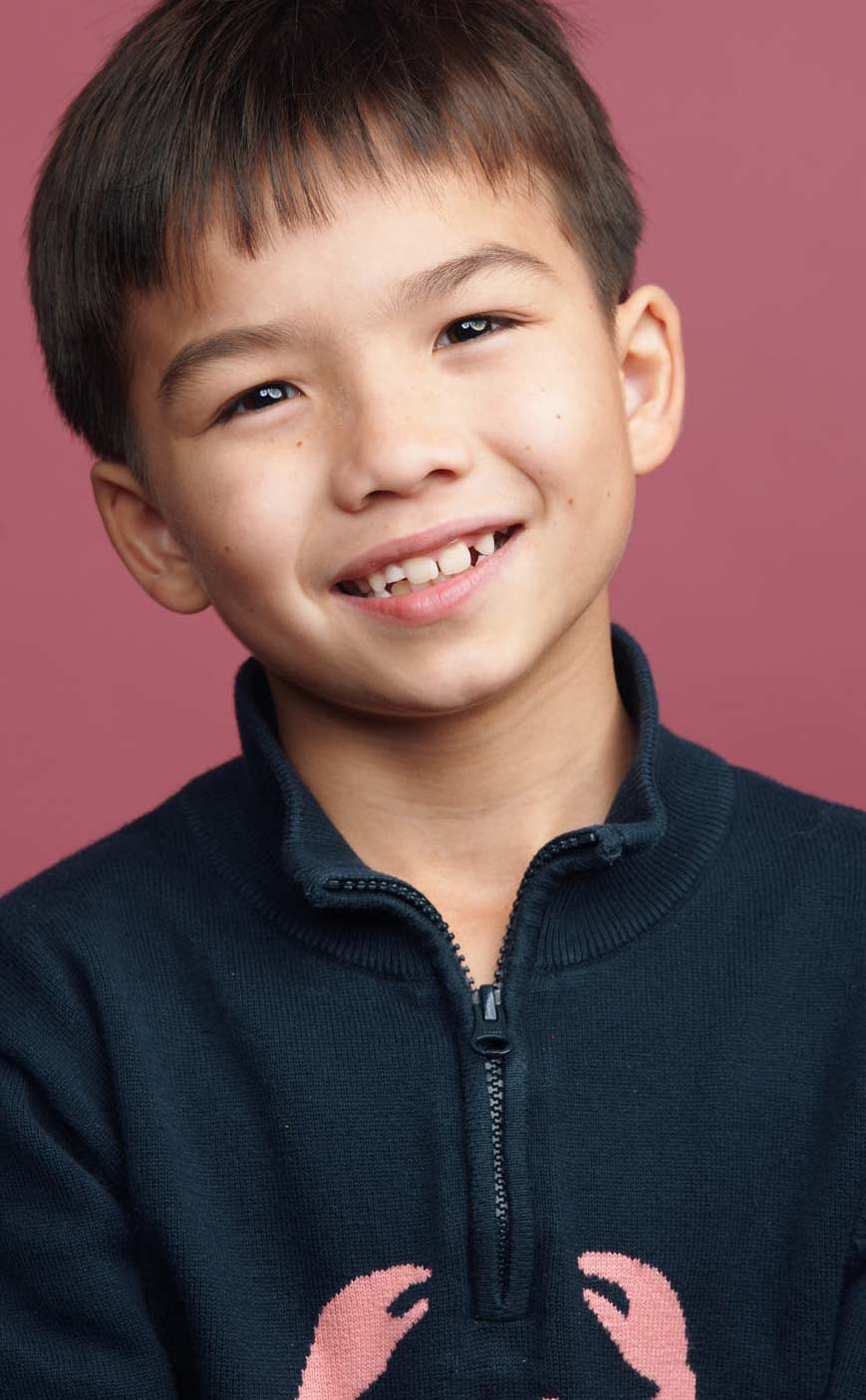 Child actor headshot of smiling boy in navy jacket for agency submission in Vancouver by Una Zhu